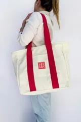 Bolso tote de tela canvas color crudo con asas largas a contratono color fucsia. Presenta un logo estampado al frente en color fucsia.