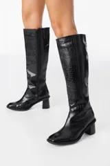 Bota bucanera de caña alta confeccionada en cuero con textura de cocodrilo, cuenta con cierre lateral y taco cuadrado.