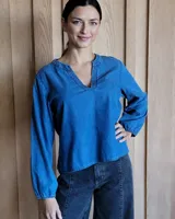 Blusa celeste de manga larga con escote en V y detalle bordado en el cuello.