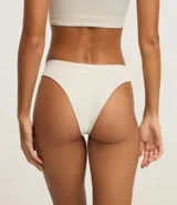 Bombacha tipo bikini de corte clásico, confeccionada en tejido de poliamida texturizado con tecnología seamless. Presenta un diseño liso en color bordó con bordes en contraste color blanco y detalle de logo bordado en el frente.