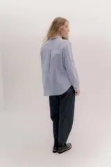 Camisa de manga larga color rosa claro con textura, cuello y puños blancos contrastantes. Los puños tienen tres botones rosados.