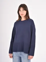 Buzo de tejido de punto color negro, con cuello redondo, mangas largas y puños anchos acanalados. Presenta un diseño con ruedo asimétrico y aberturas laterales.
