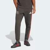 Pantalón deportivo Adidas de felpa, color gris oscuro, con diseño de tiro medio y corte clásico. Presenta las icónicas tres bandas laterales en color rojo, logo de Audi Revolut F1 Team en la pierna derecha y logo de Adidas en la izquierda. Incluye cintura con cordón ajustable y bolsillos laterales.