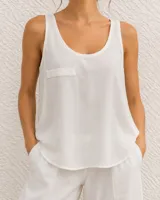 Musculosa blanca de lino con escote redondo, corte holgado, dobladillo curvo y un pequeño bolsillo aplicado en el pecho.