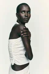 Top negro con cuello halter, escote pico y espalda descubierta. Presenta detalle de frunces laterales y cierre frontal con botones.