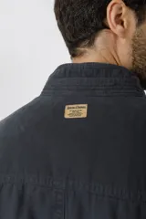 Campera de algodón color azul marino con cuello alto, cierre frontal con cremallera y botones a presión, cuatro bolsillos frontales con solapa y puños con botón.