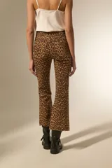Pantalon jean de tiro alto con corte flare y ruedo desflecado, estampado con diseño animal print de leopardo en tonos marrones.