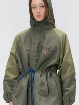 Campera tipo piloto con capucha, cierre frontal con botones y detalle de costuras en zigzag. Presenta cordones ajustables en la cintura y capucha, puños elásticos y logo bordado en el pecho.