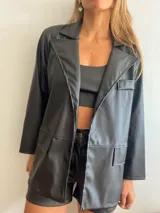 Blazer negro de cuerina con solapas, bolsillos frontales y corte holgado.