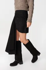 Falda de cuero marrón con diseño asimétrico, presenta un detalle de lazo frontal drapeado que crea una caída lateral más larga.