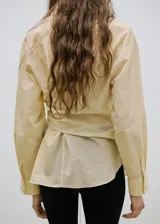 Camisa amarilla de manga larga con diseño cruzado y lazo para atar en la cintura.