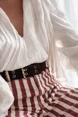 Cinto de cuero con hebilla cuadrada metálica y doble hilera de ojales decorativos.