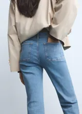 Jeans flare de tiro medio color celeste, confeccionados en tejido denim de algodón con elasticidad. Presentan cierre delantero con cremallera y botón, trabillas para cinturón y dos bolsillos de parche en la parte delantera.
