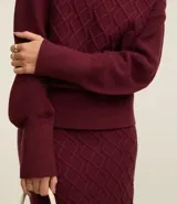 Suéter de manga larga confeccionado en tricot, con cuello alto y diseño de bordado de rombos en relieve. Presenta puños y ruedo acanalados.