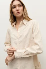 Camisa de manga larga color beige con diseño texturizado en tono sobre tono, cuello clásico y cierre frontal con botones.