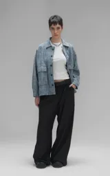 Campera de denim rígido con textura de trama única, corte oversize, cuello camisero, cierre frontal con botones y bolsillos delanteros con solapa.