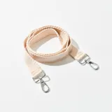 Correa de tela color beige con mosquetones metálicos plateados en los extremos.