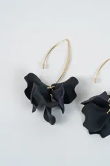 Aros colgantes con diseño de pétalos en color negro y azul oscuro, montados sobre un gancho de metal dorado.