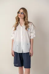 Camisa blanca de manga larga con bordados de motivos playeros.