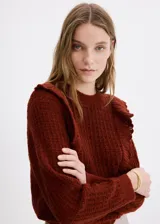 Sweater marrón de punto con volantes en los hombros, cuello redondo y mangas largas.