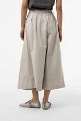 Pantalón wide leg de color blanco, de silueta amplia y gran movimiento, con pliegues delanteros que aportan volumen y estructura, y cintura definida.