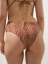 Malla enteriza con estampado animal print tipo dálmata en tonos marrón y blanco, con escote en V pronunciado, copas triangulares y tirantes finos ajustables con anudado en la espalda.