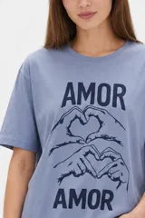 Remera de algodón negro con cuello redondo y diseño holgado, con estampado frontal de líneas horizontales blancas y un corazón rojo superpuesto.