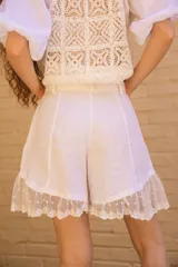 Short de lino blanco, tiro alto, con silueta relajada y detalle de tul bordado con lunares y puntilla en el bajo.