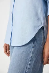 Camisa de manga larga color celeste, con cuello clásico, cierre frontal con botones y un bolsillo aplicado en el pecho.
