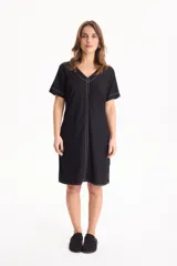 Vestido corto de lino color negro, con escote en V, manga corta y bolsillos laterales, destacado por costuras a contratono en color blanco.