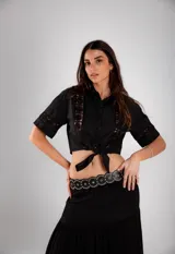 Camisa corta negra de manga corta con broderie en el frente y mangas. Se ata con un nudo en la parte delantera.