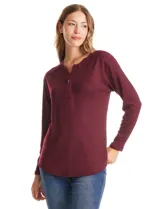 Buzo de tejido fino con diseño henley, cuello redondo con abertura frontal y cierre de botones. Presenta detalles acanalados en hombros, puños y ruedo, con una silueta cómoda y terminación redondeada en la parte inferior.