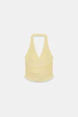 Top halter de tejido semitransparente con estampado de lunares plumeti, escote en pico y detalle de frunces en los laterales.