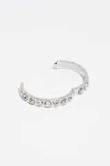 Pulsera rígida de metal plateado con cristales facetados en forma de corazón incrustados a lo largo de su superficie, equipada con un cierre de bisagra.