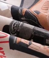 Buzo canguro con capucha color beige, confeccionado en mezcla de algodón y poliéster con interior de felpa suave. Presenta cordones de ajuste en la capucha, bolsillo estilo canguro en la parte delantera y estampa localizada en el pecho con temática de automovilismo.