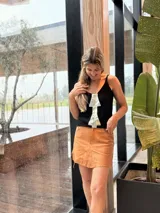Musculosa de tejido de punto gris, con tirantes finos, escote en V y un llamativo aplique frontal de cuero plateado en forma de flecha.