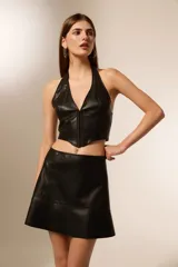 Top estilo corset de cuero sintético negro, con escote halter profundo y cierre frontal con alamares.