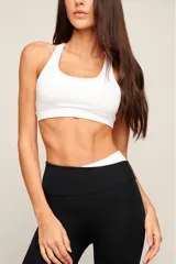 Top deportivo blanco de poliamida con diseño de espalda nadador, breteles medios y banda elástica inferior para mayor soporte. Cuenta con forro interno y entrada para copas removibles.
