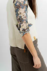 Chaleco tejido en lana merino, de color crudo, con cuello redondo y diseño clásico sin mangas.