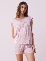 Conjunto de pijama marca René Rofé, compuesto por short y remera de tejido soft estampado con flores rosas sobre fondo blanco. Remera de escote en V con aplique de puntilla, botones y detalle plisado. Short con cintura elastizada.