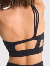 Top deportivo de un solo hombro, color negro, con diseño de tirantes triples elásticos en la espalda y almohadillas removibles.