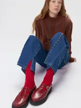 Sweater de punto con diseño de rayas verticales en tonos negro y gris oscuro. Presenta cuello alto tipo polera, mangas largas con puños ajustados y ruedo elástico. Incluye un pequeño bordado en color rojo en el pecho.