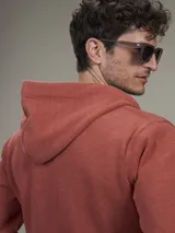 Buzo tipo hoodie con cierre frontal completo, capucha con cordones ajustables y bolsillos laterales. Confeccionado en tejido de algodón con textura jaspeada.