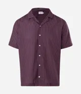 Camisa de manga corta con cuello solapa, cierre frontal de botones y diseño a rayas verticales. Confeccionada en algodón con textura.