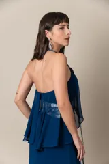 Vestido largo de fiesta color azul, confeccionado en gasa con corsé drapeado y breteles bordados. Presenta una capa de gasa que nace de los breteles. Incluye un cinturón plateado.