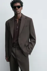 Blazer de corte regular confeccionada en tejido de lana. Presenta cuello con solapas de muesca, cierre frontal de un botón y manga larga con puños abotonados. Cuenta con bolsillos de vivo en el pecho, bolsillos con solapa en la cadera y aberturas en la parte posterior.