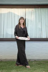 Conjunto de dos piezas color negro, compuesto por un pantalón ancho de tiro alto con detalle de encaje en el ruedo y una blusa holgada de manga larga con escote drapeado y nudo frontal.