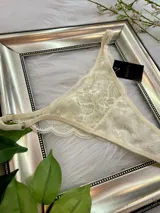 Pack de tres tangas de encaje con tiras regulables, en colores rosa, beige y rojo.