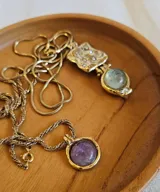 Collar dorado con cadena fina y dije con forma irregular con incrustaciones y dije colgante con piedra prehnita redonda y dije cuadrado pequeño. 