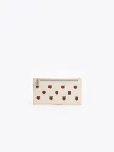 Billetera rectangular de cuero vacuno color beige con estampado de frambuesas y cierre superior metálico.